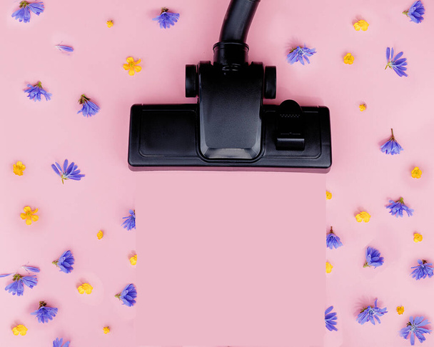Brush powerful black vacuum cleaner on pink background among flowers. Strength, power, environmental friendliness. Good cleaning, fresh clean air. Help mistress of house. Concept photo. Top view - Photo, Image