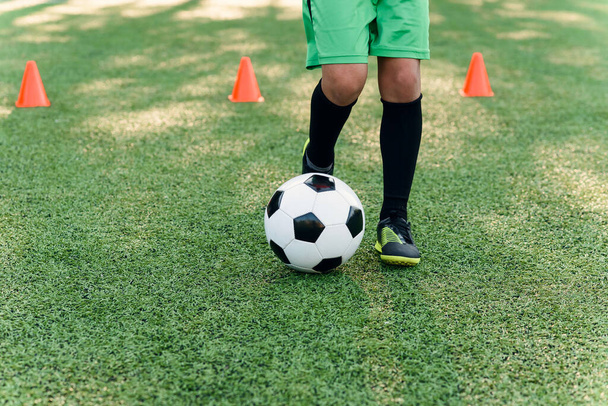 Detail soccer player kicking ball on field. Soccer players on training session. Detail soccer background. Close up of legs and feet of footballer on green grass - Fotó, kép