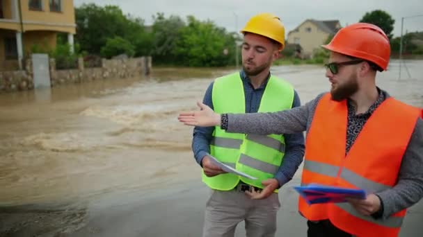 Two male engineers solve the flood problem. Natural disaster major flooding - Πλάνα, βίντεο
