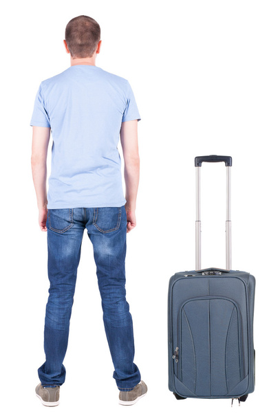 Back view of young man traveling with suitcase. - Foto, immagini