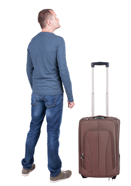 Back view of young man traveling with suitcase. - Photo, image