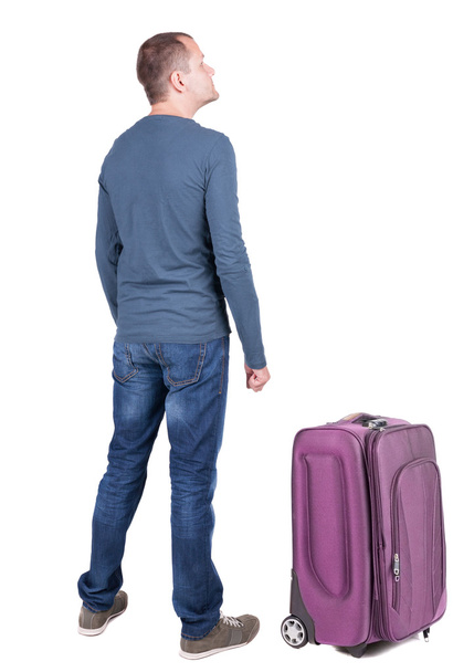 Back view of young man traveling with suitcase. - Foto, Imagen