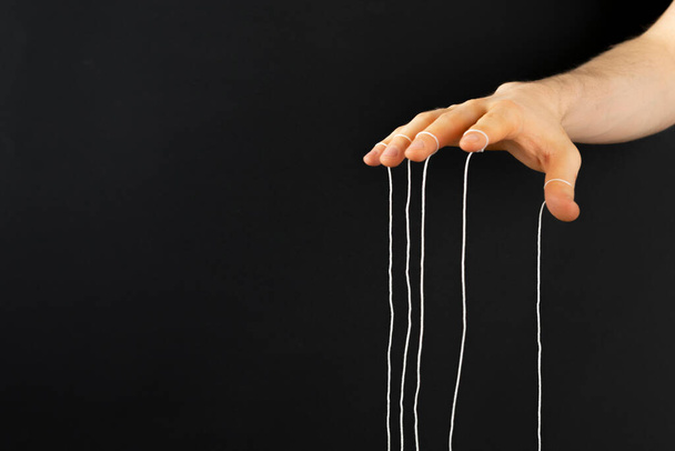 Puppenspielerhand mit Seilen an den Fingern kontrolliert das Denken der Menschen - Foto, Bild