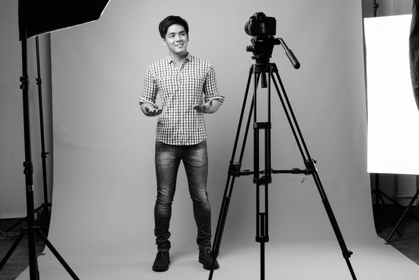 Studio shot of young handsome Filipino man against gray background in black and white - Φωτογραφία, εικόνα