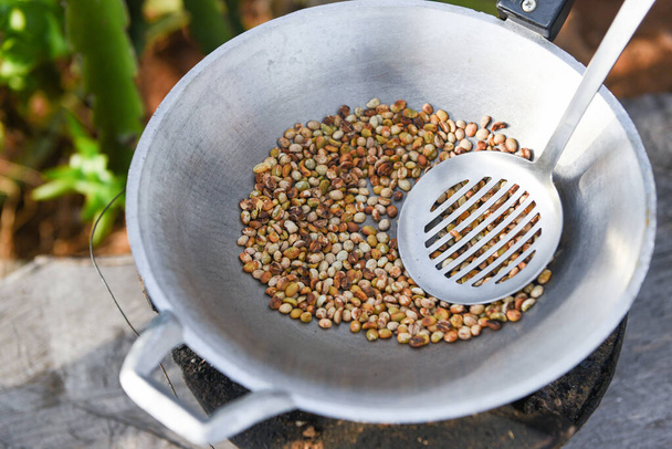 grains de café torréfiés sur poêle chaude dans la campagne montagnarde / grains de café frais crus - Photo, image