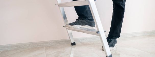 Κλείστε τα πόδια των εργαζομένων στη σκάλα ανεβείτε στην κορυφή προς τον τοίχο με αντίγραφο χώρο - Φωτογραφία, εικόνα
