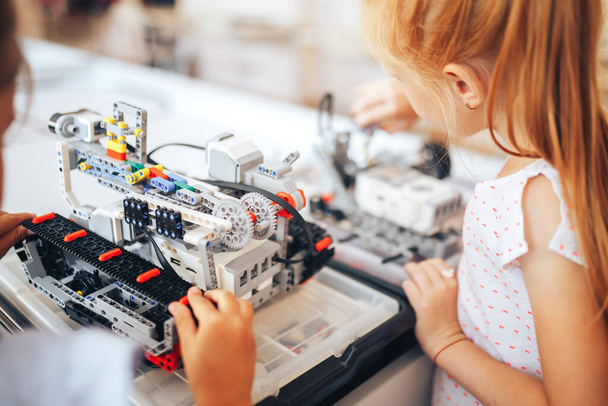 Két iskoláslány robotika órán tanul, összeraknak egy robottervezőt.. - Fotó, kép