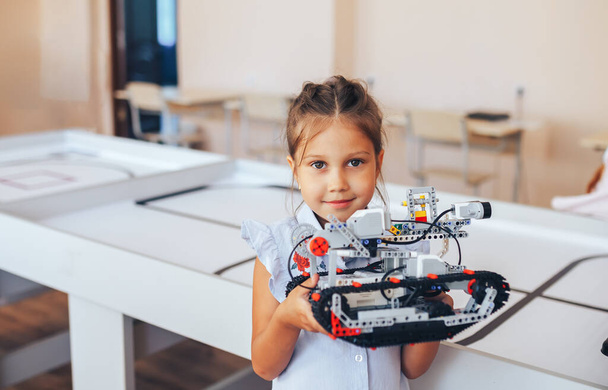 Schoolgirl holding constructor robot in robotics class. - 写真・画像