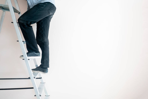 fechar os pés trabalhadores na escada subir para o topo contra a parede com espaço de cópia - Foto, Imagem