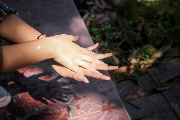 Κορίτσι πλένει τα χέρια με νερό κάτω από το φως του ήλιου. Στοιχεία του χεριού έννοιας της υγιεινής. - Φωτογραφία, εικόνα