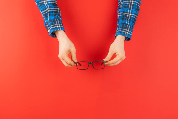 hand holding black glasses isolated against the colorful background, minimalism simple concept - Photo, Image