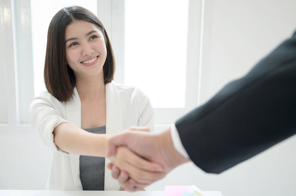 Красивая молодая азиатская деловая женщина улыбается и пожимает руки сделки принимают партнерские бизнес в офисе - Фото, изображение