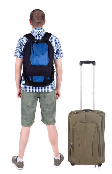 Back view of young man traveling with suitcase. - Фото, изображение