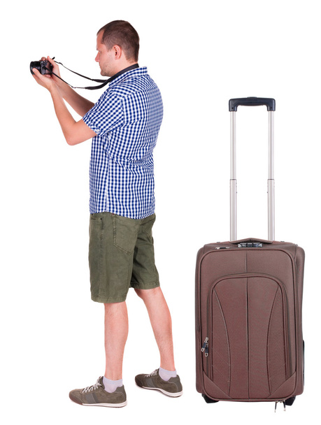 Back view of man photographing traveling with suitcase. - Фото, изображение