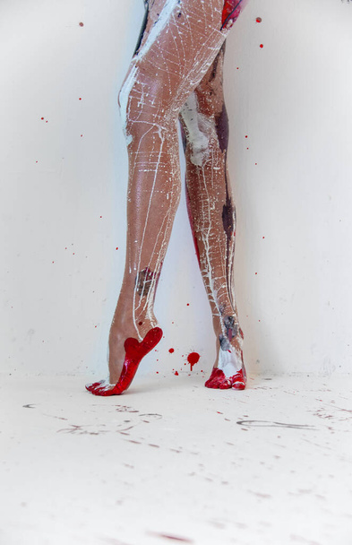 hermosas piernas y pies de un joven sexy artísticamente abstracto negro, blanco, rojo, mujer pintada bailarina de puntillas en el piso de estudio artistas pintados artísticamente abstractos, espacio de copia
. - Foto, imagen