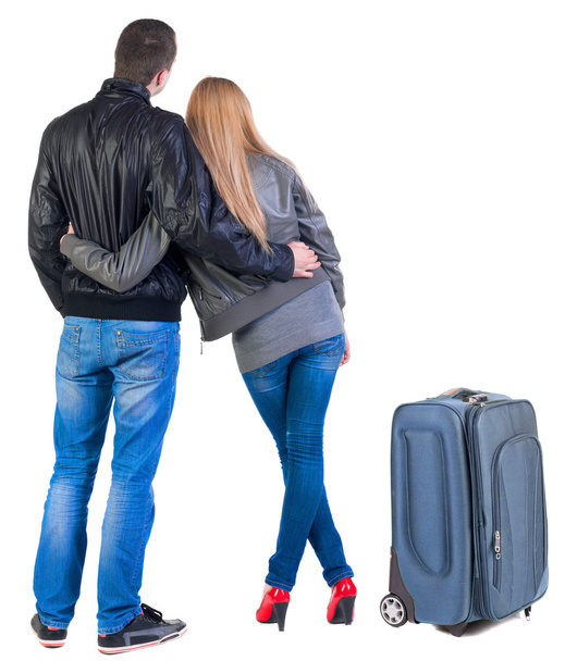 Back view of young couple traveling with suitcase. - 写真・画像
