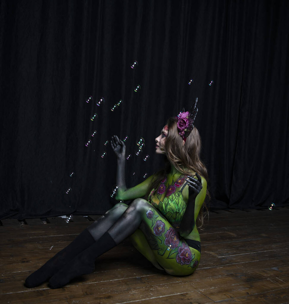 красива дівчина з обличчям і тілом, намальованим під бургундськими півоніями, позує з мильними бульбашками
 - Фото, зображення