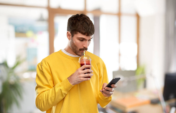 homme avec smartphone et jus de tomate au bureau - Photo, image