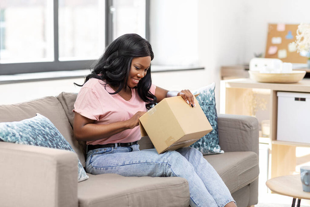 african american woman opening parcel box at home - 写真・画像