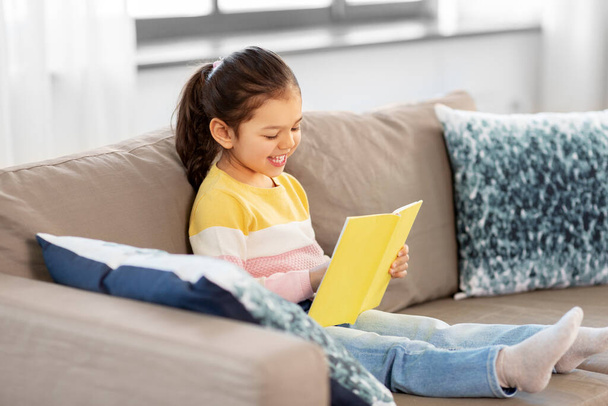 feliz sorrindo menina leitura livro em casa - Foto, Imagem