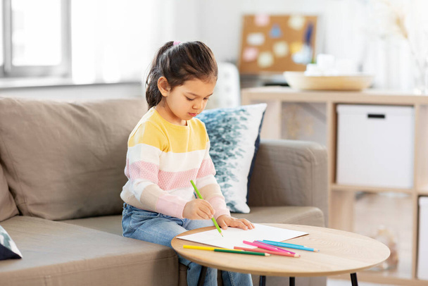 little girl drawing with coloring pencils at home - Foto, imagen