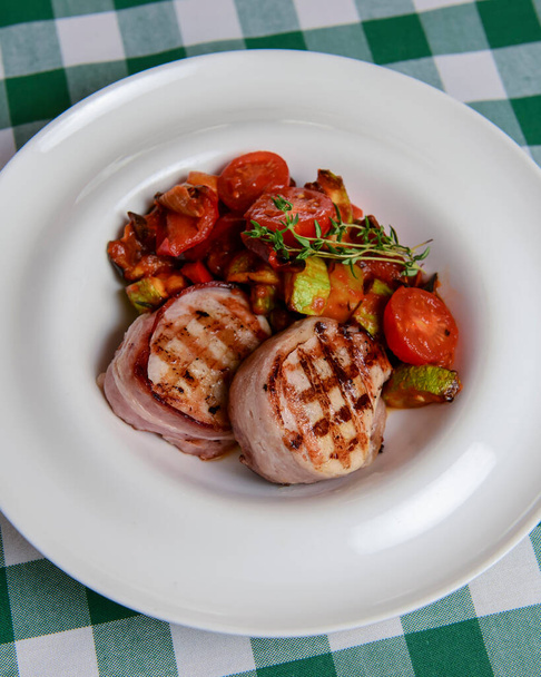 Fresh meat and vegetables prepared on grill. Bbq meat and veggies. Seasonal summer meal concept, barbecue concept. Served in a white plate over green plaid table cloth. - 写真・画像