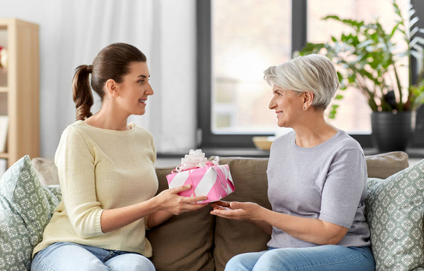 adult daughter giving present to her senior mother - Foto, immagini