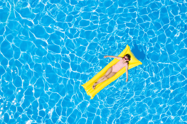 Cute little girl with inflatable mattress in swimming pool, top view. Space for text  - Фото, зображення