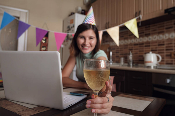 Girl celebrating birthday online in quarantine time. Woman celebrating her birthday through video call virtual party with friends. Authentic decorated home workplace. Coronavirus outbreak 2020. - Photo, Image