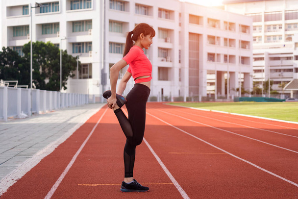 Портрет молодої жінки бігун розігрівається і розтягується перед тренуванням вранці на міському стадіоні. Здоровий і рекреаційний запас фото
. - Фото, зображення