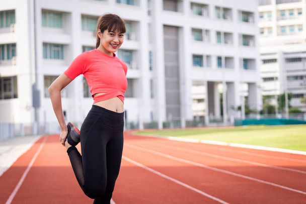 Portré egy fiatal női futó melegszik és nyújtózkodik edzés előtt reggel a városi stadionban. Egészséges és rekreációs stock fotó. - Fotó, kép