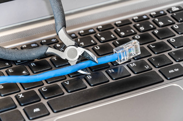 Pliers cutting internet cable on computer keyboard - Photo, Image