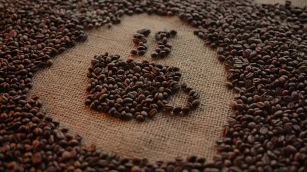 Schematic drawing coffee cup made of roasted coffee beans on burlap surface - Materiaali, video