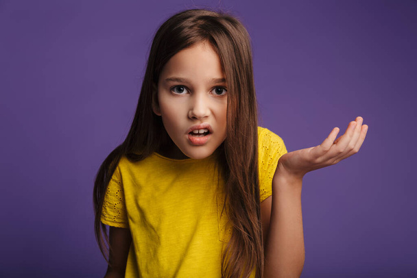 Photo of displeased nice girl looking at camera and holding copyspace isolated over purple background - Photo, Image