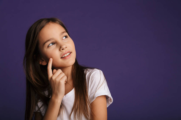 Photo of pleased beautiful girl posing and looking upward isolated over purple background - Photo, image