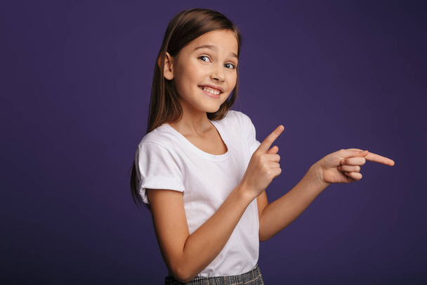 Photo of joyful attractive girl smiling and pointing fingers aside isolated over purple background - Fotó, kép
