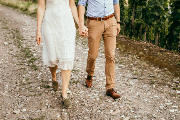 Romantyczna para trzymająca się za ręce stojąca na zielonej trawie - Zdjęcie, obraz