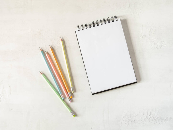 Blank sheet notebook with copy space for text and multicolored graphite pencils on white background. Flat lay, top view girl work business concept for lifestyle blog - Φωτογραφία, εικόνα