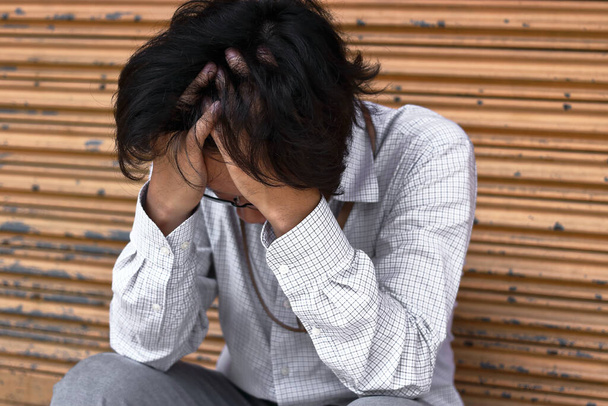 Werklozen gestrest jonge Aziatische zakenman in pak bedekking gezicht met de handen. Falen en ontslag concept. - Foto, afbeelding