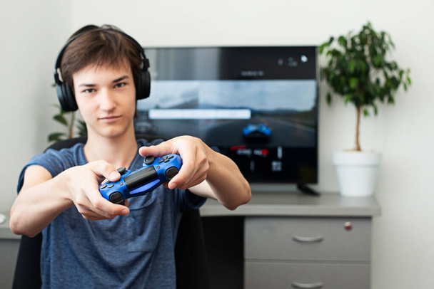 Nastolatek chłopiec online gra w grę komputerową ze słuchawkami i joystickiem, konsola do gier. - Zdjęcie, obraz