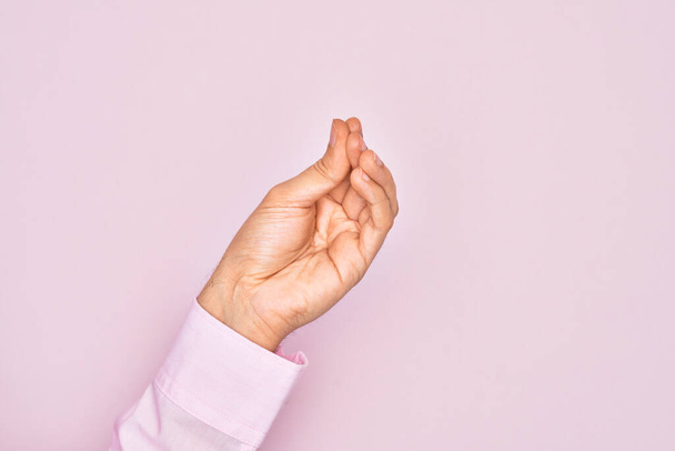 Hand of caucasian young man showing fingers over isolated pink background doing Italian gesture with fingers together, communication gesture movement - Photo, Image