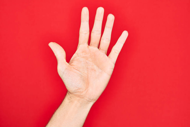 Kéz a kaukázusi fiatalember mutató ujjak felett elszigetelt piros háttér számlálás 5 mutatja öt ujját - Fotó, kép