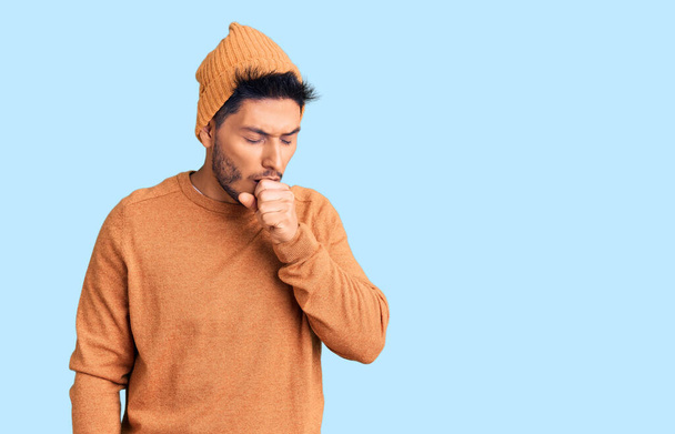 Bello latino americano giovane uomo che indossa maglione invernale e cappello di lana sensazione di malessere e tosse come sintomo di freddo o bronchite. concetto di assistenza sanitaria.  - Foto, immagini