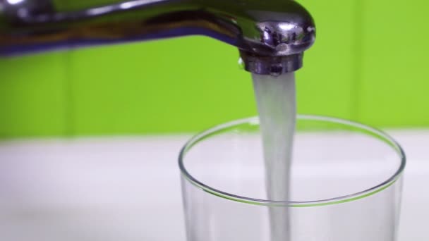 Lasin täyttäminen puhtaaseen juomaveteen, kunnes se tulvii - luonnonvarojen tuhlausta - Materiaali, video