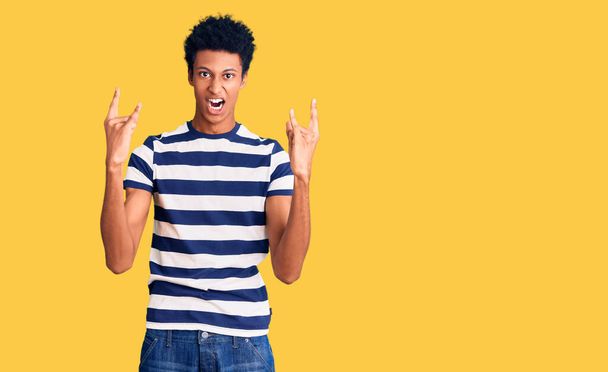 Young african american man wearing casual clothes shouting with crazy expression doing rock symbol with hands up. music star. heavy concept.  - Fotografie, Obrázek