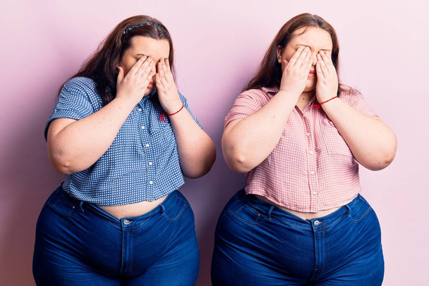Young plus size twins wearing casual clothes rubbing eyes for fatigue and headache, sleepy and tired expression. vision problem  - Photo, Image