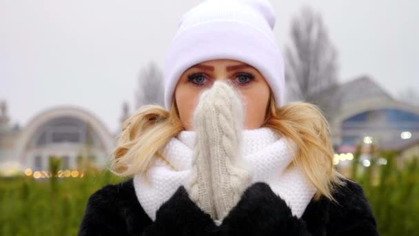 close-up bevroren vrouw in witte hoed, sjaal, wanten warmt handen, wrijven palmen - Video