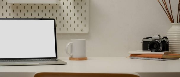 Close up άποψη του σύγχρονου χώρου εργασίας με mock up laptop, φλιτζάνι καφέ, φωτογραφική μηχανή, βιβλία χρονοδιάγραμμα, διακοσμήσεις και χώρο αντίγραφο σε λευκό τραπέζι - Φωτογραφία, εικόνα