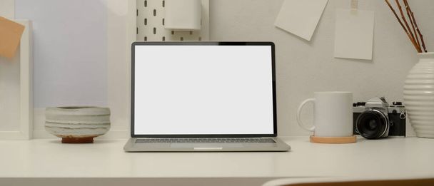 Close up άποψη του σύγχρονου χώρου εργασίας με mock up laptop, φλιτζάνι καφέ, κάμερα, βιβλία χρονοδιάγραμμα, διακοσμήσεις σε λευκό τραπέζι στο γραφείο στο σπίτι - Φωτογραφία, εικόνα