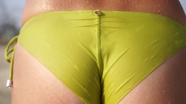 Kropelki wody spływają po skórze seksownej kobiety w stroju kąpielowym na plaży. - Materiał filmowy, wideo